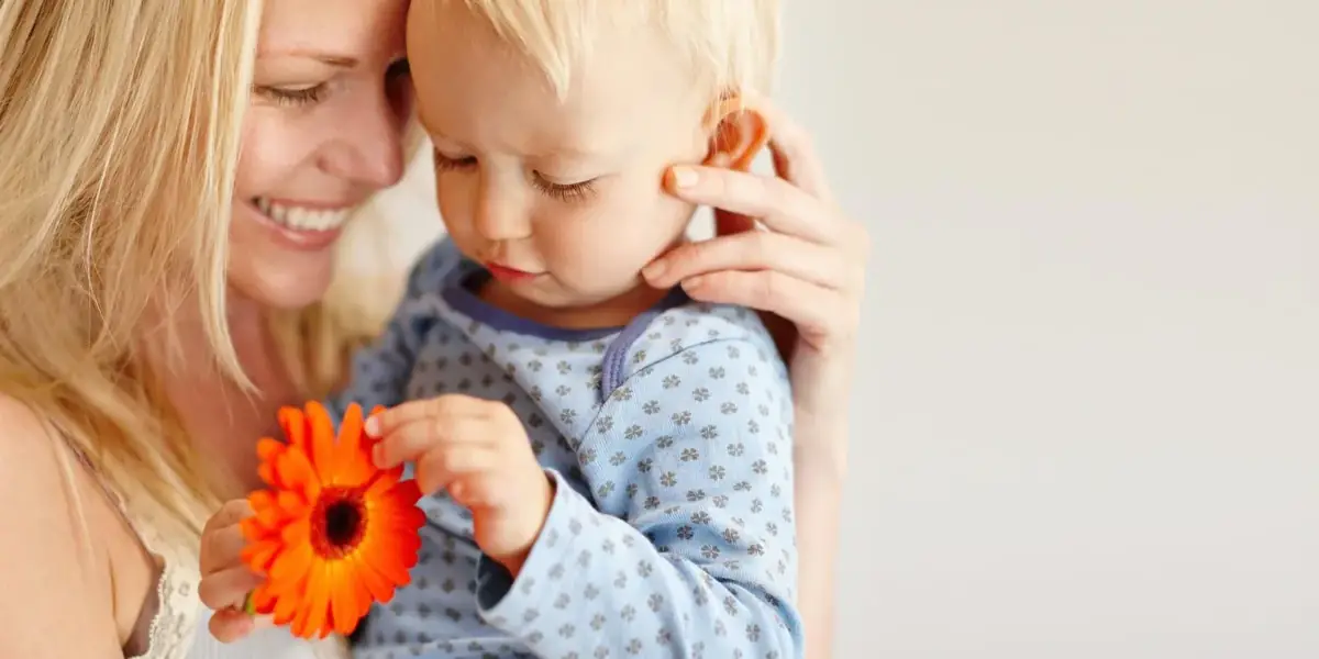 Mutter hält ihr Kleinkind lächelnd im Arm